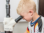 Kindertag im Robert Koch-Institut: Ein Junge schaut durch ein Mikroskop. Quelle: © RKI